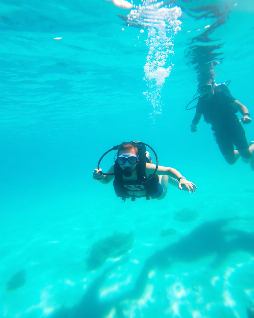 First-time diver in clear turquoise Caribbean water with an instructor nearby